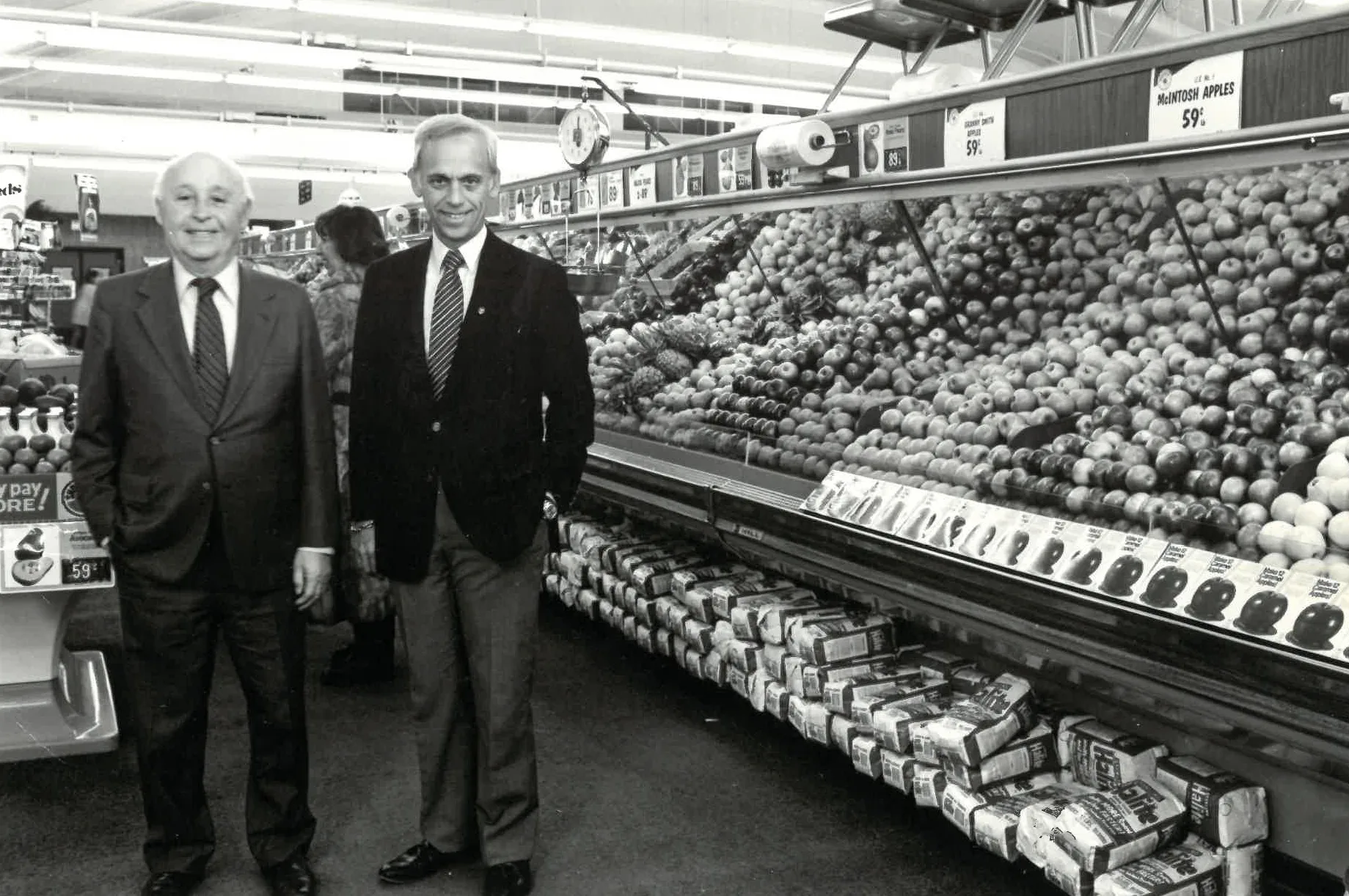 A black and white photo of two businessmen in a grocery store